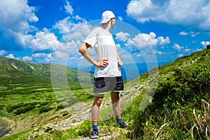 Man hiker relaxing on top of hill and admiring beautiful mountain valley view