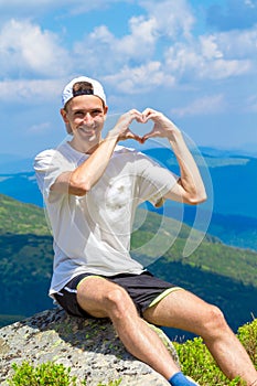 Man hiker relaxing on top of hill and admiring beautiful mountain valley view