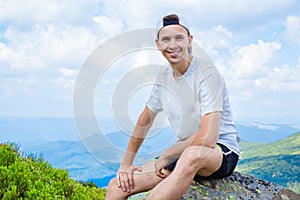 Man hiker relaxing on top of hill and admiring beautiful mountain valley view