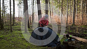 Man hiker sets up camping tent in the fall forest on backpacking expedition. Traveler setting an overnight tent in the