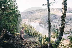 A man hiker sitting on a cliff edge enjoying scenic view