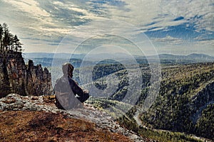 Man hiker sitting on top of mountain in rainy day, it is wet bad weather.