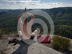 Man hiker sitting on the top of the mountain in yoga pose