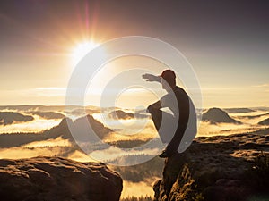 Man hiker squatting and shadowing eyes. Misty mountain valley and adventure photo