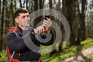 Man hiker taking photo with smart phone in forest