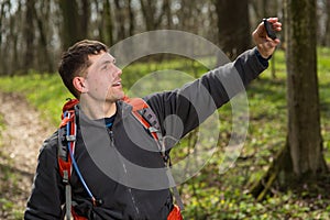 Man hiker taking photo with smart phone in forest