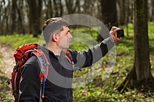 Man hiker taking photo with smart phone in forest