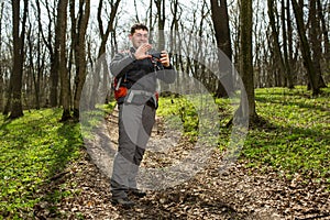 Man hiker taking photo with smart phone in forest