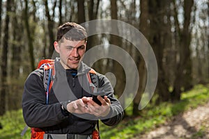 Man hiker taking photo with smart phone in forest