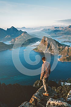 Man hiker traveling in Norway solo hiking in mountains of Lofoten islands outdoor traveler standing on cliff edge