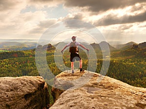 Man hiker with trekking poles and backpack on a top of a mountain. Traveler with Backpack