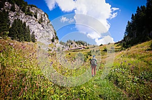 Man hiker walking on meadow in mountain.