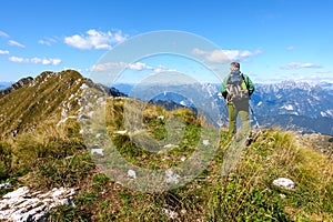 Man hiker walking on top of mountain against blue sky