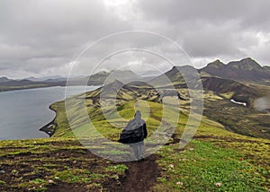 Man hiking alone into the wild admiring volcanic landscape with heavy backpack. Travel lifestyle adventure wanderlust concept