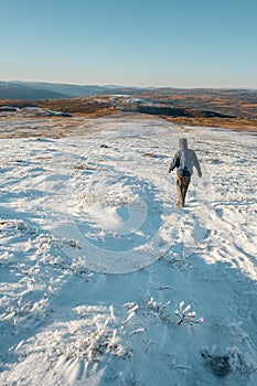 Man hiking in beautiful winter landscape snow view from mountain Litjskarven in Norway in sunnlight