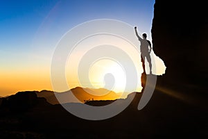 Man hiking climbing silhouette success in mountains sunset