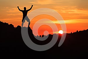 Man hiking climbing silhouette in sunset mountains