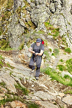Man hiking on difficult mountain trail with hanging cable