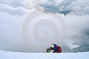 Man hiking with dog in beautiful winter forest in mountain