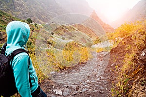 Man hiking down the Xo Xo valley. Golden backlit sun shining behind the mountain peak in background. Santo Antao Island