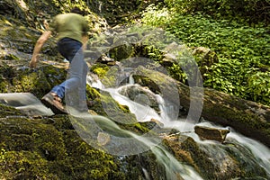 Man hiking over waterfall with motion blur.