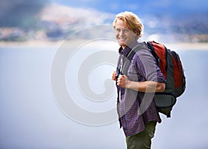 Man, hiking and portrait in nature for travel, adventure and wellness by ocean, sea and vacation in Europe. Face of an