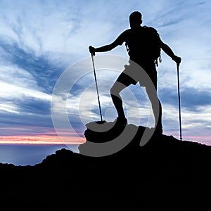 Man hiking silhouette in mountains, ocean and sunset