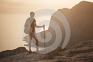 Man hiking at sunset mountains with heavy backpack