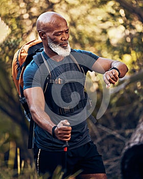 Man, hiking and watch on adventure in nature for trekking, fitness and cardio exercise. Senior black person with