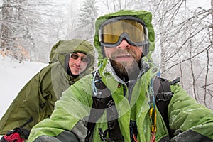 Man is hiking in winter forest on cloudy day