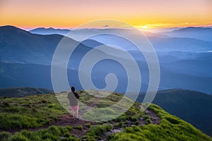 Man on the hill with green grass and mountain valley at sunset