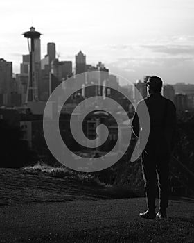 Man on a hillside, gazing out over a sprawling cityscape of Seattle, Washington, USA in grayscale