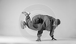 A man hip hop dancer or bboy freezes in one pose on a white background. Bboy doing stylish stunts.