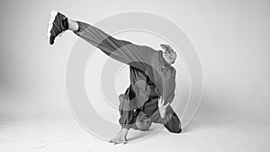 A man hip hop dancer or bboy freezes in one pose on a white background. Bboy doing stylish stunts.