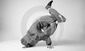 A man hip hop dancer or bboy freezes in one pose on a white background. Bboy doing stylish stunts.