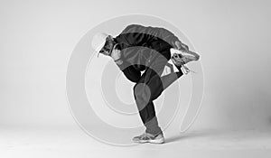 A man hip hop dancer or bboy freezes in one pose on a white background. Bboy doing stylish stunts.