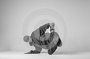 A man hip hop dancer or bboy freezes in one pose on a white background. Bboy doing stylish stunts.