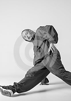 A man hip hop dancer or bboy freezes in one pose on a white background. Bboy doing stylish stunts.