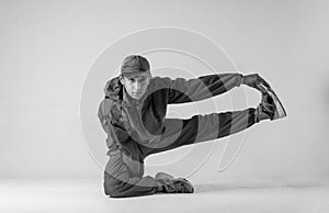 A man hip hop dancer or bboy freezes in one pose on a white background. Bboy doing stylish stunts.