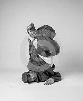 A man hip hop dancer or bboy freezes in one pose on a white background. Bboy doing stylish stunts.