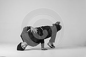 A man hip hop dancer or bboy freezes in one pose on a white background. Bboy doing stylish stunts.