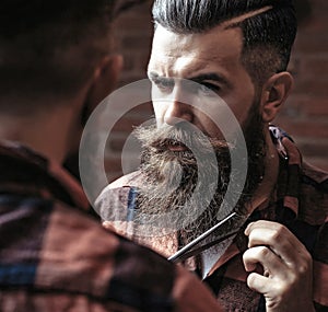 Man hipster cutting beard. Barber scissors and straight razor, barber shop, suit. Vintage barber shop, shaving. Portrait