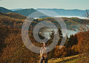 Man hipster hiker enjoying view above the clouds on meadow of mountain ridge against mountains