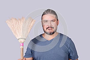 A man in his 30s holding an old broom. A househusband doing the the house cleanup. Cleanliness concept