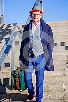 Man in his 50s walking down stairs with his suitcase