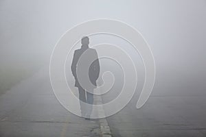 Man with his back walking through the fog street