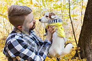 Man with his dog at autumn park. Guy playing with jack russell terrier outdoors. Pet and people concept.