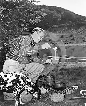 Man and his dog camping and preparing food