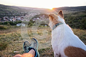 Muž jeho pes sledování západ slunce na kopec přes obec bod z 