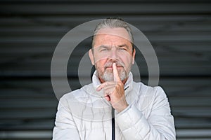 Man in his fifties has a finger thoughtfully on his mouth